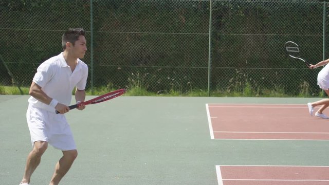  Male & female tennis players playing 2 different games on outdoor court