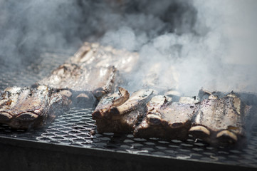 Ribs cooking on a smoky barbecue grill