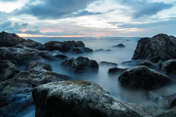 Smooth ocean as long exposure during sunset at Koh Lanta with Stones in the sea and Phi Phi islands in the horizon, Koh Lanta, Thailand, Asia