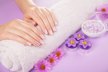 Obraz na płótnie Canvas Beautiful pink and silver manicure with flowers and spa essentials