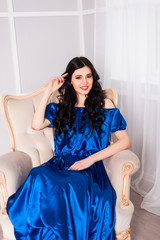 young woman in elegant blue gray evening dress indoors with beautiful interior