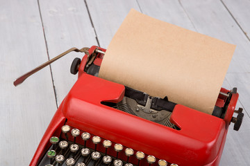 Red vintage typewriter with blank paper sheet on white wooden table