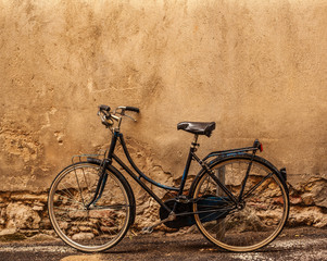 Fototapeta na wymiar Verona. Retro styled image of vintage old Bicycle on Street in Italy, parking near wall with copy space.