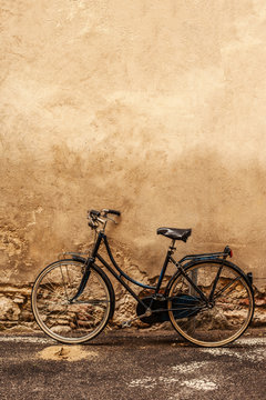 Verona.  Retro styled image of vintage old  Bicycle on Street in Italy, parking near wall with copy space.