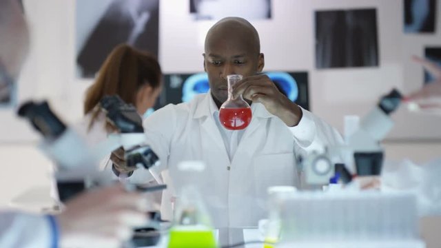 Scientific research team working in the lab, focus on man experimenting with chemicals