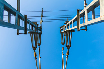 Bottom symmetric view of railway traction line towers on the background of clear sky
