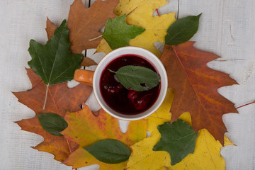 Concept of autumn comfort - colorful leaves and cup of tea on white wooden background. Top view