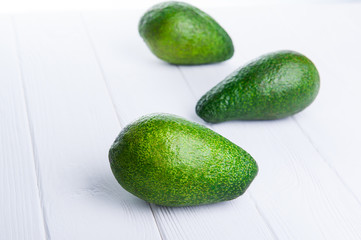 Three avocados on the white wooden table . Healthy living, diet, raw eating, vegetable fats concept background. Selective focus, space for text