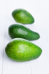 Three avocados on the white wooden table . Healthy living, diet, raw eating, vegetable fats concept background. Selective focus, space for text