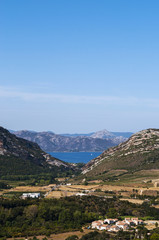 Fototapeta na wymiar Corsica, 28/08/2017: vista panoramica del paesaggio selvaggio dell'Alta Corsica con le montagne circondate da colline verdi, vigneti e campi di grano