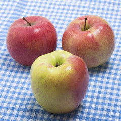 Three ripe apples on a kitchen towel