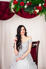 young woman in elegant blue gray evening dress indoors with beautiful interior