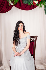 Fototapeta premium young woman in elegant blue gray evening dress indoors with beautiful interior