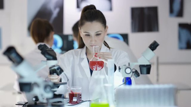 Scientific research team working in the lab, focus on woman experimenting with chemicals