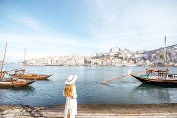 Young woman traveler enjoying beautiful cityscape view Douro river and traditional portuguese boats...