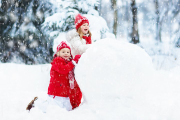 Fototapeta na wymiar Kids building snowman. Children in snow. Winter fun.