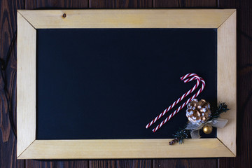 Wooden blackboard with place for your text with christmas candys and fir-cone.