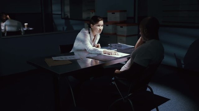  Female police detective questioning a crime suspect in interrogation room