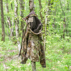 Hunter's camouflage jacket hanging on the tree in the wood