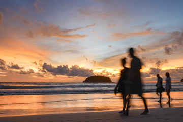 Fototapeta premium blurred people at the beach with twilight cloudy sky.There is an island in the sea