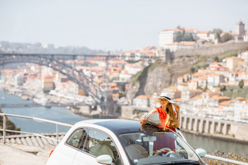 Young woman in red dress traveling by car in Porto city, Portugal