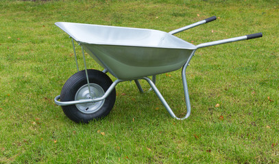 Wheelbarrow on a green grass field. Garden metal wheelbarrow cart.