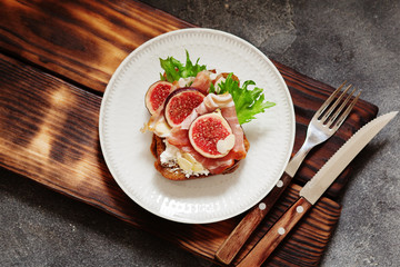Sandwich with ham, ricotta cheese and figs on white plate
