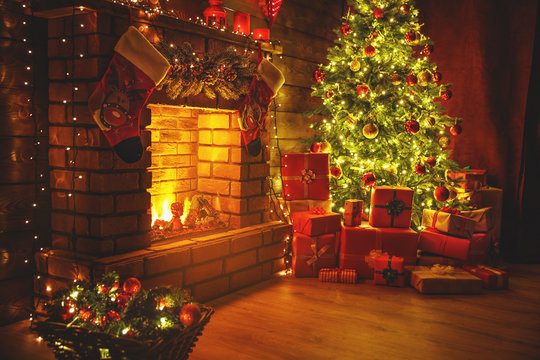interior christmas. magic glowing tree, fireplace gifts in  dark