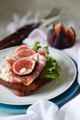 Sandwich with ham, ricotta cheese and figs on white plate