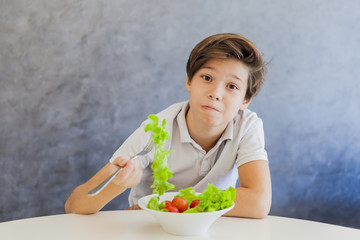 Cute teen boy eating salad