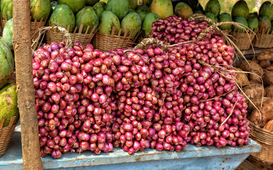 Red onion and mango on display for a sale. Close up. Market stall. Organic food.