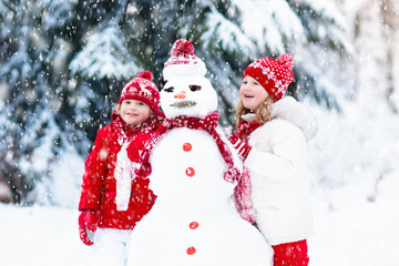 Kids building snowman. Children in snow. Winter fun.