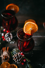 christmas hot mulled wine with spices, candle and traditional New Year decorations and orange on wooden background