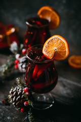 christmas hot mulled wine with spices, candle and traditional New Year decorations and orange on wooden background