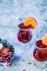 christmas hot mulled wine with spices, candle and traditional New Year decorations and orange on...