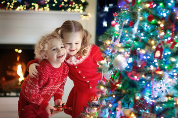 Fototapeta na wymiar Children at Christmas tree. Kids at fireplace on Xmas eve