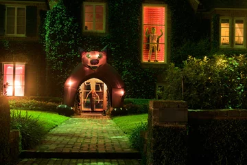 Gordijnen The house is decorated for Halloween: a man in a window, a skeleton riding on a man, and a monster at the entrance. Night © Irina K.