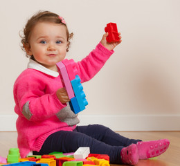 Toddler baby girl playing with rubber building blocks.