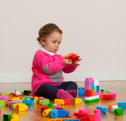Toddler baby girl playing with rubber building blocks.