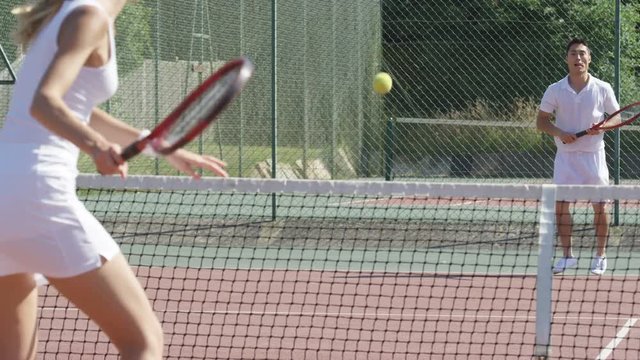  Competitive female tennis player playing against male opponent