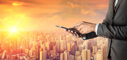 Businessman with digital tablet on city background
