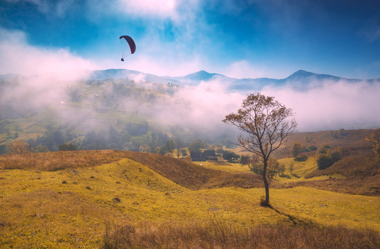 Paraglide silhouette flying above foggy carpathian hills