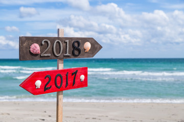Metal 2018 and 2017 number on the wooden beach sign standing at the beach.