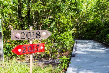 Metal 2018 and 2017 number on the wooden beach sign standing at the beach path.