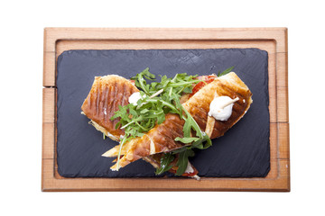 Sandwich with ham,tomato, cucumber and arugula on the wooden cutting board