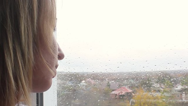 Girl looking out of window a rainy day
