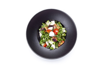 Italian mozzarella cheese and tomato salad with tomatoes and crisp crunchy fried bread cretins, view from above on a black  plate on white background