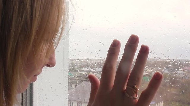 Girl looking out of window a rainy day