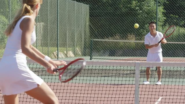  Competitive female tennis player playing against male opponent