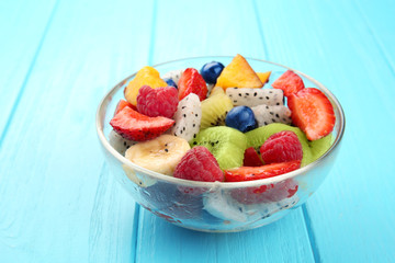 Bowl with delicious fruit salad on wooden table